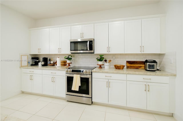 kitchen featuring white cabinetry, backsplash, appliances with stainless steel finishes, and light tile patterned floors