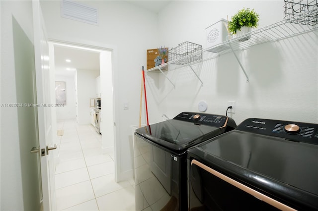 laundry room with independent washer and dryer and light tile patterned floors