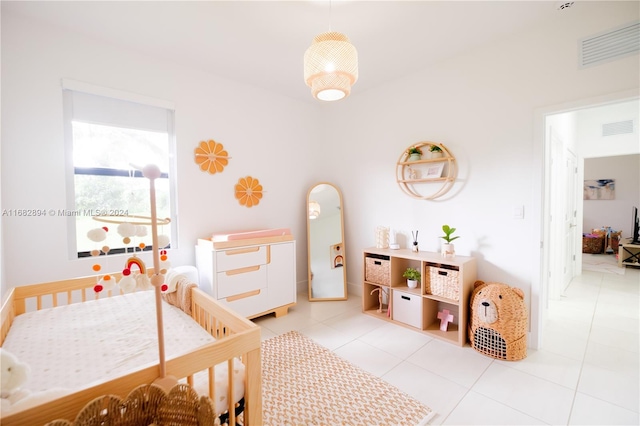 bedroom featuring a nursery area and light tile patterned floors