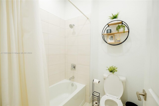 bathroom featuring toilet and shower / bath combination with curtain