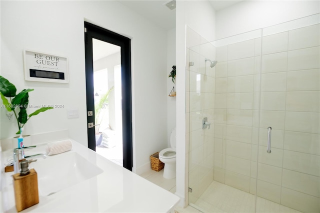 bathroom with a shower with door, vanity, toilet, and tile patterned floors