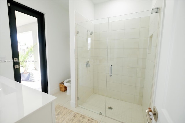 bathroom with toilet, tile patterned flooring, vanity, and a shower with door