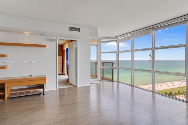 unfurnished room with a wealth of natural light, hardwood / wood-style floors, and a water view