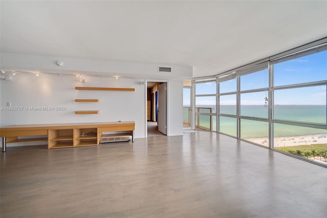 interior space featuring expansive windows, plenty of natural light, a water view, and a beach view