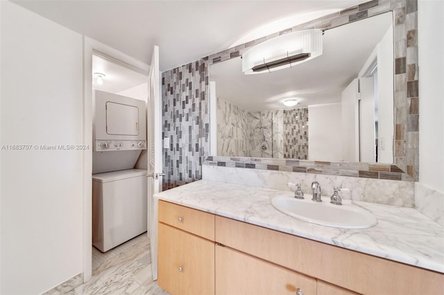 bathroom featuring decorative backsplash, stacked washing maching and dryer, walk in shower, tile walls, and vanity