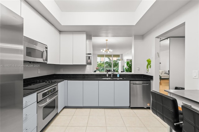 kitchen with decorative light fixtures, stainless steel appliances, white cabinets, a sink, and modern cabinets