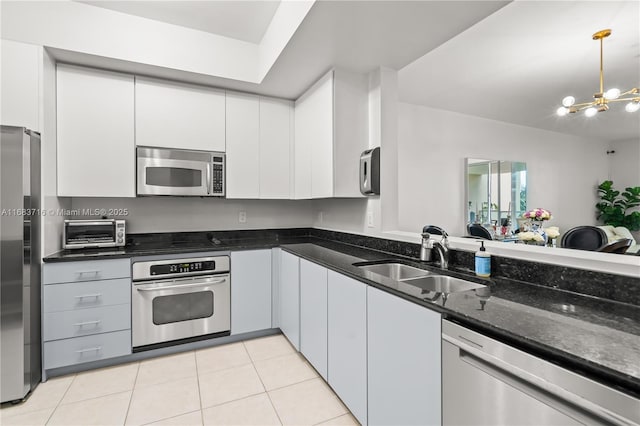 kitchen with a toaster, stainless steel appliances, a sink, white cabinets, and dark stone counters