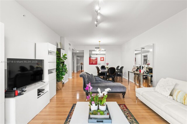 living room featuring track lighting, a chandelier, and light hardwood / wood-style flooring