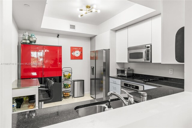 kitchen with light tile patterned flooring, sink, white cabinetry, a notable chandelier, and stainless steel appliances