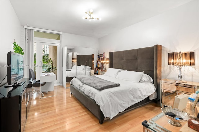 bedroom featuring light wood-style floors, access to exterior, a chandelier, and a closet