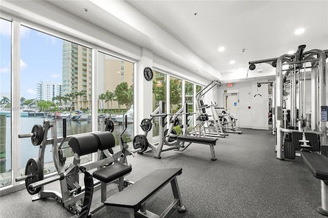 exercise room featuring recessed lighting, a city view, and a water view