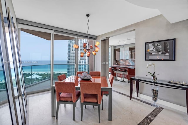 dining room with a water view, a chandelier, plenty of natural light, and a wall of windows