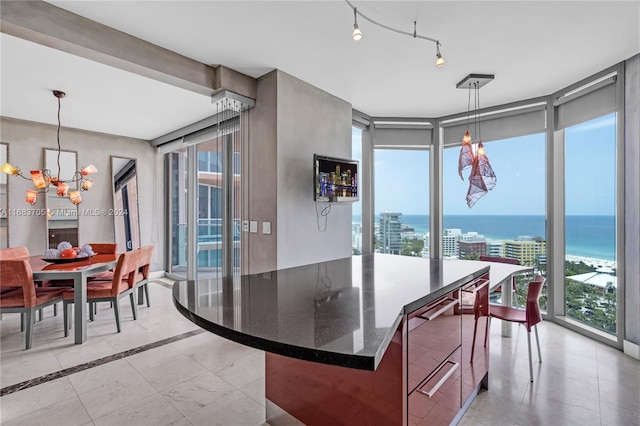 dining room featuring plenty of natural light, a chandelier, a water view, and floor to ceiling windows