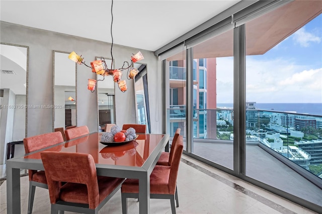 dining space with a water view, a notable chandelier, and a healthy amount of sunlight