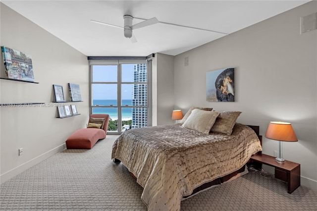 bedroom with a water view, ceiling fan, carpet, and a wall of windows