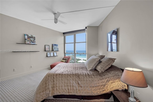 carpeted bedroom with a water view and ceiling fan