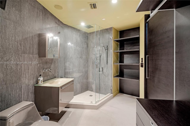 bathroom featuring vanity, a shower with shower door, toilet, and tile walls