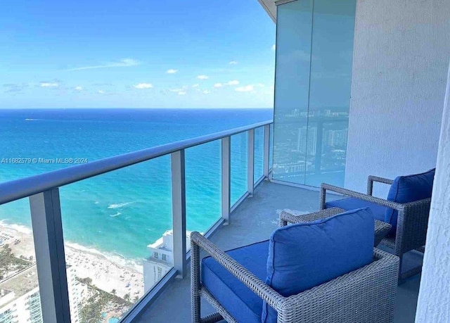 balcony featuring a water view and a beach view