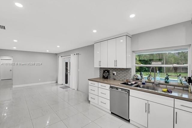 kitchen with white cabinetry, decorative backsplash, dishwasher, and sink