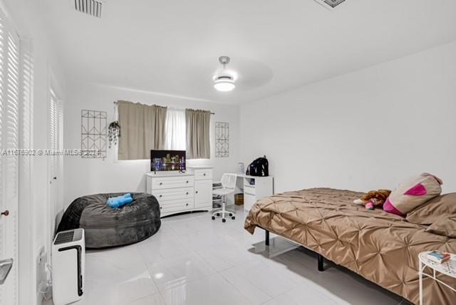 tiled bedroom featuring multiple windows and ceiling fan