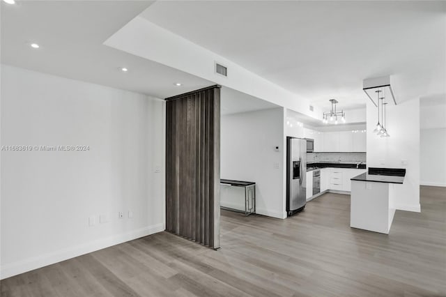 kitchen with a kitchen breakfast bar, light hardwood / wood-style flooring, hanging light fixtures, stainless steel appliances, and white cabinets