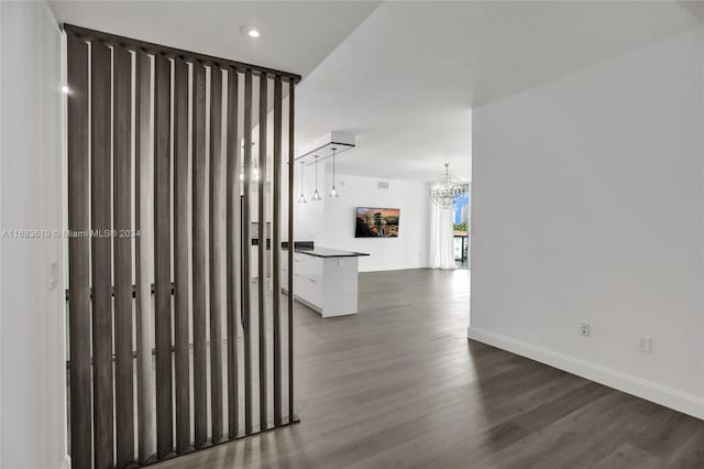 hall with a notable chandelier and dark hardwood / wood-style flooring