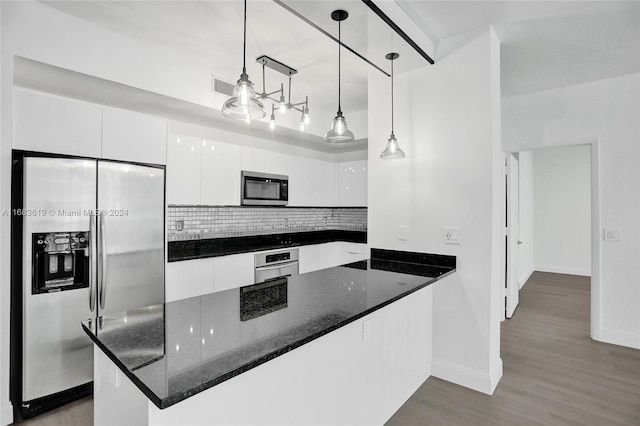 kitchen with kitchen peninsula, hanging light fixtures, stainless steel appliances, dark stone countertops, and white cabinetry