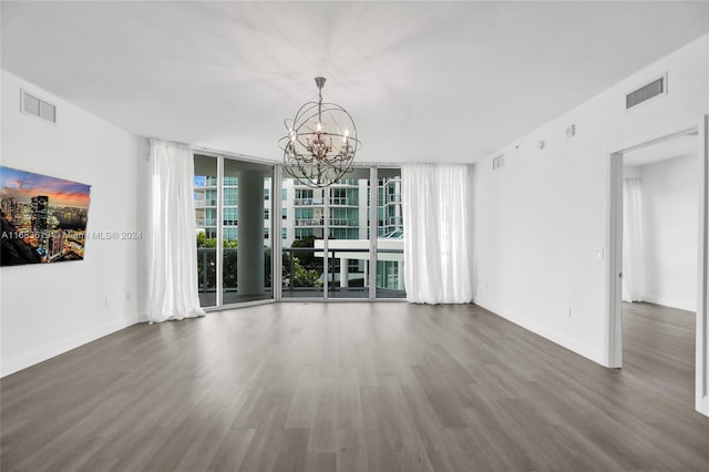 unfurnished living room featuring a notable chandelier, a wall of windows, and dark hardwood / wood-style flooring