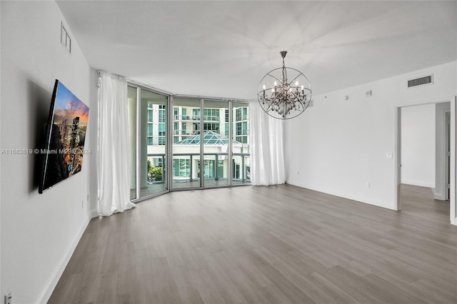 unfurnished room featuring floor to ceiling windows, a chandelier, and hardwood / wood-style floors