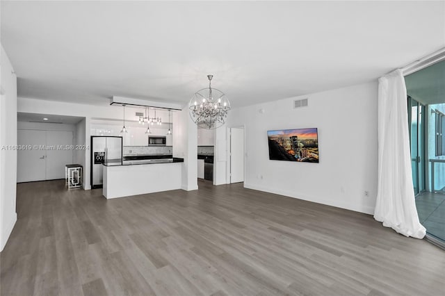 unfurnished living room with dark wood-type flooring and an inviting chandelier