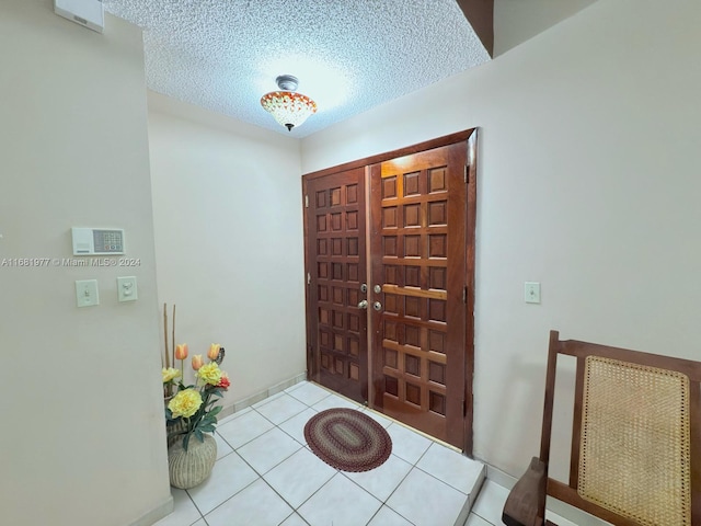 foyer entrance with a textured ceiling and light tile patterned flooring