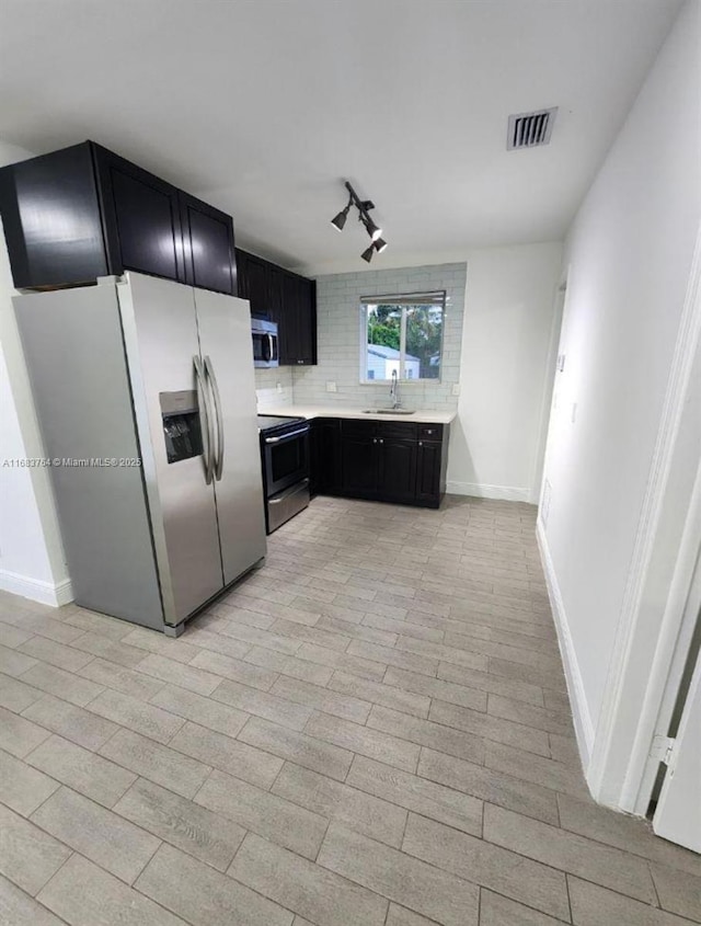 kitchen featuring light countertops, visible vents, dark cabinetry, stainless steel appliances, and a sink