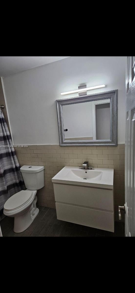 bathroom featuring vanity, toilet, tile walls, and hardwood / wood-style floors