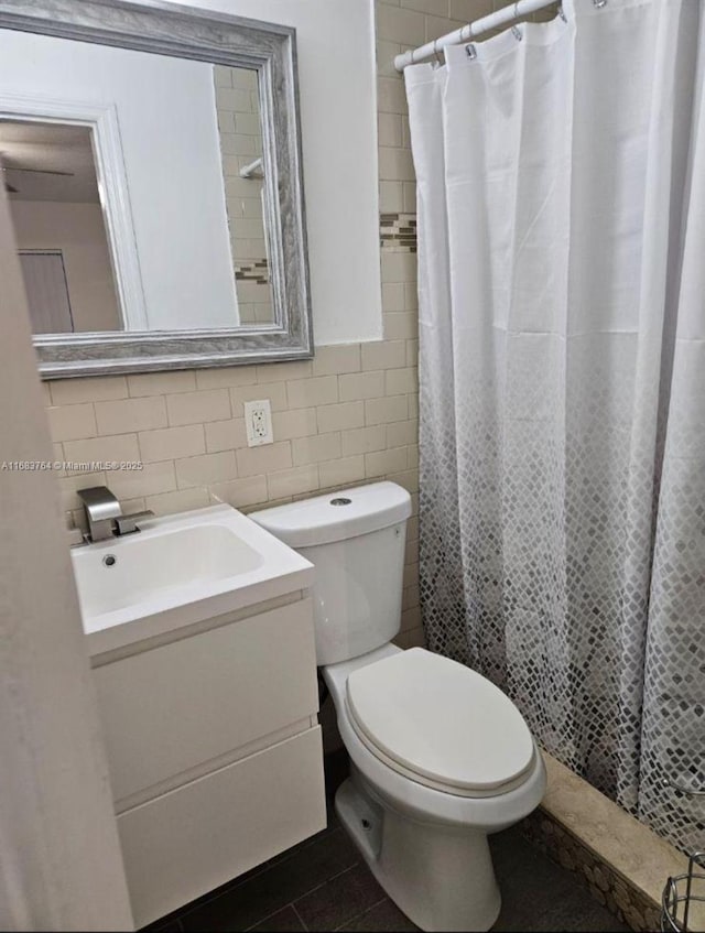 bathroom with a shower with shower curtain, vanity, tile walls, and toilet