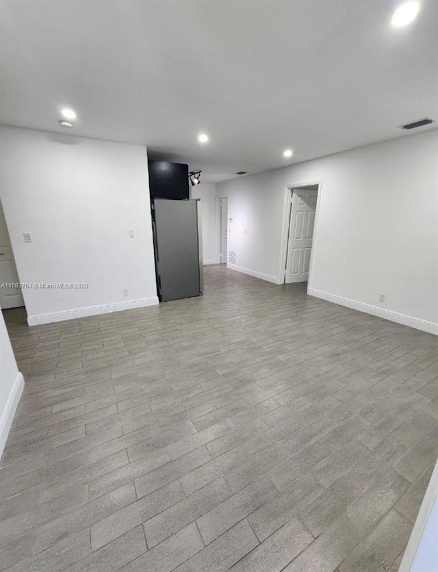 basement featuring visible vents, baseboards, freestanding refrigerator, and recessed lighting