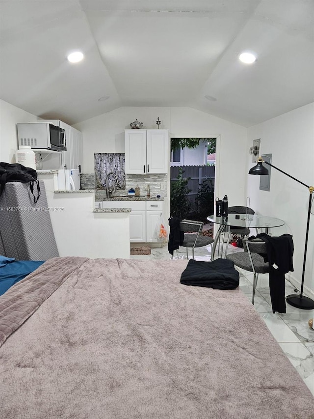 interior space featuring marble finish floor, a sink, and vaulted ceiling