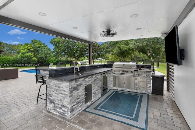 view of patio with wine cooler, an outdoor kitchen, area for grilling, and a wet bar