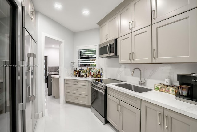 kitchen featuring appliances with stainless steel finishes, sink, gray cabinets, decorative backsplash, and light tile patterned floors