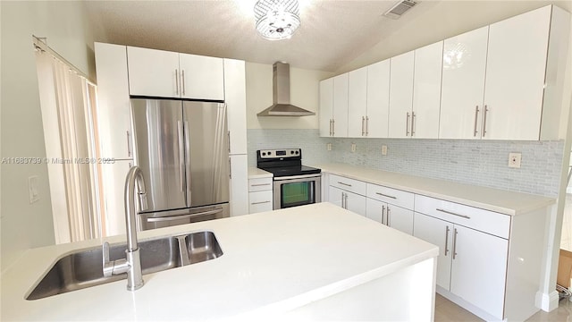 kitchen featuring wall chimney exhaust hood, sink, tasteful backsplash, appliances with stainless steel finishes, and white cabinets