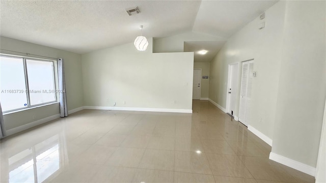 unfurnished room with light tile patterned floors, a textured ceiling, and lofted ceiling