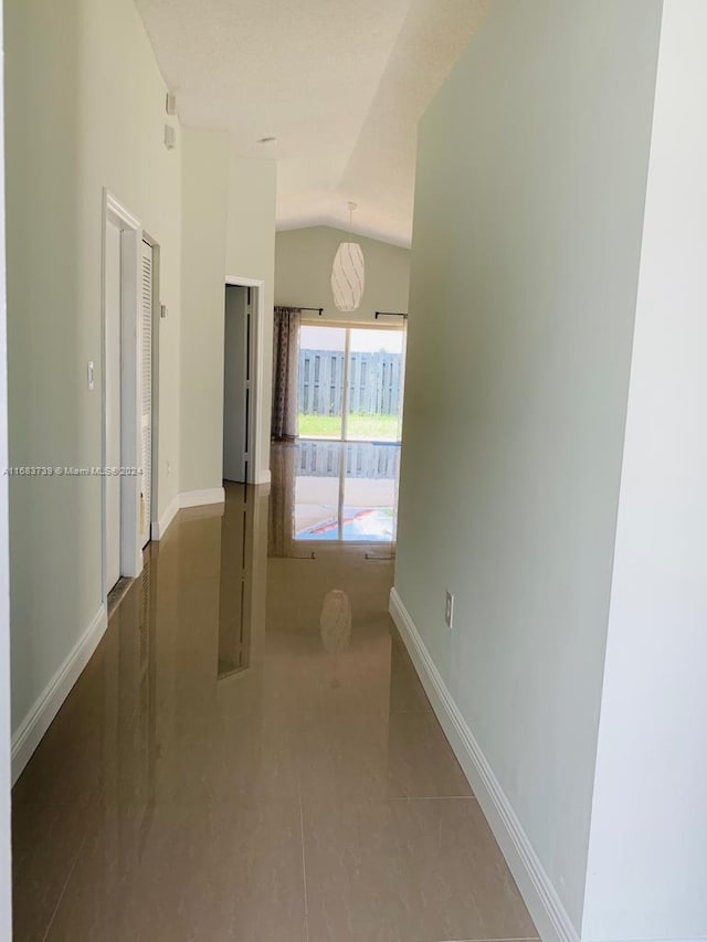 hallway featuring tile patterned flooring and lofted ceiling