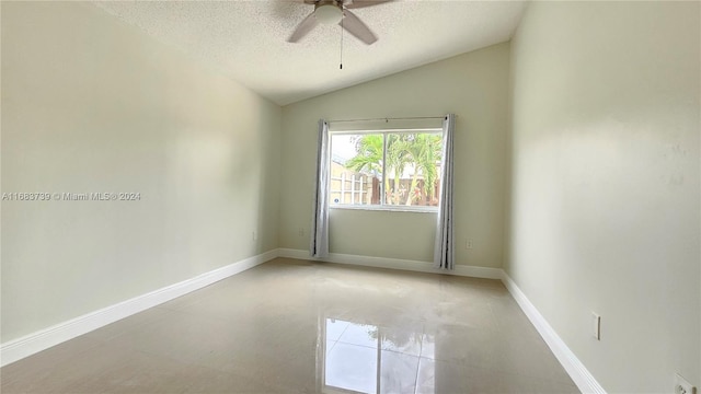 empty room with ceiling fan, light tile patterned flooring, lofted ceiling, and a textured ceiling