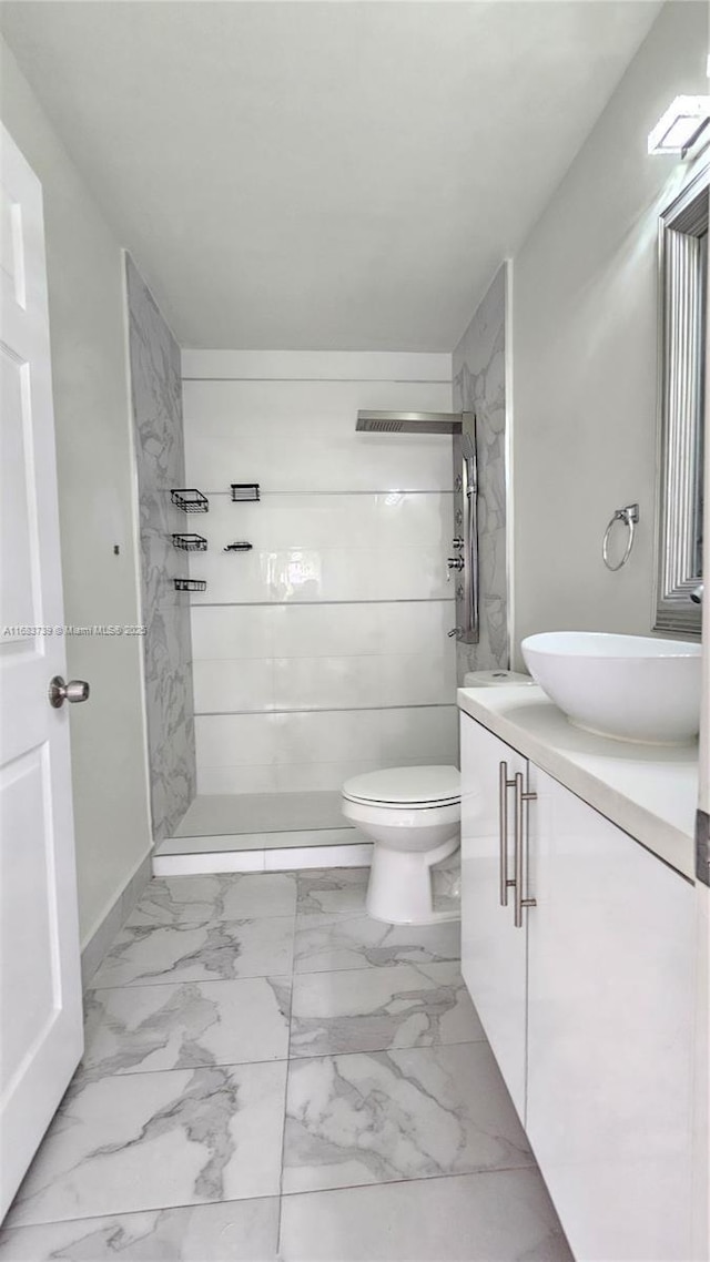 bathroom featuring toilet, marble finish floor, a stall shower, and vanity