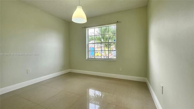 tiled empty room with a textured ceiling