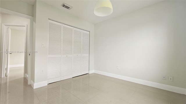 unfurnished bedroom featuring a closet, tile patterned flooring, visible vents, and baseboards