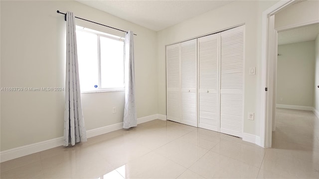 unfurnished bedroom with light tile patterned flooring, a textured ceiling, and a closet