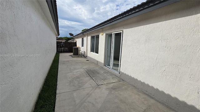 view of property exterior with a patio, central air condition unit, fence, and stucco siding