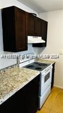 kitchen featuring dark brown cabinets, electric range, light tile patterned floors, range hood, and light stone counters