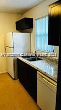 kitchen featuring sink, light tile patterned flooring, and white appliances