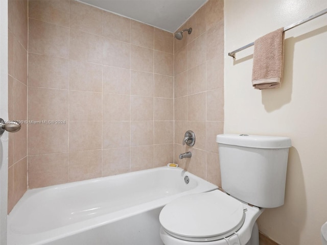 bathroom with toilet and tiled shower / bath